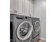 Modern laundry room featuring sleek, front-load washer and dryer, with extra cabinet space at 3072 W Glacier Dr, Monrovia, IN 46157