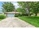 Charming single-story brick home with a blue garage door and a long driveway, surrounded by mature trees and greenery at 3636 Oakwood Dr, Anderson, IN 46011