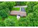 Aerial view showcases a brick home, patio deck, driveway, and a backyard surrounded by lush greenery and fencing at 4132 Tincher Rd, Indianapolis, IN 46221