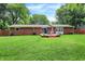This home features a spacious backyard, brick exterior, a wooden fence, and an inviting deck with patio furniture at 4132 Tincher Rd, Indianapolis, IN 46221