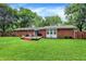 Charming backyard featuring a brick home, deck, patio furniture, and a well-manicured lawn with a wooden fence at 4132 Tincher Rd, Indianapolis, IN 46221