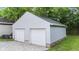 Two-car garage boasts white siding, white doors, concrete base, and a gravel driveway at 6029 English Ave, Indianapolis, IN 46219