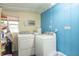 The laundry room has a washer and dryer, window AC unit, and blue wood paneled walls at 6805 Jackson St, Indianapolis, IN 46241