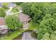 Aerial shot of a home nestled among lush trees, featuring a pond, balcony, and stone patio at 7175 Scarlet Oak Dr, Noblesville, IN 46062