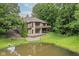 Rear exterior view of a home showcasing balconies, a patio, a pond, and a well-maintained lawn at 7175 Scarlet Oak Dr, Noblesville, IN 46062