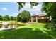 Exterior view of a brick home with balconies overlooking a picturesque pond and manicured lawn at 7175 Scarlet Oak Dr, Noblesville, IN 46062