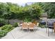 Outdoor patio set on a concrete slab, perfect for dining al fresco with lush greenery and a grill at 7629 Candlewood Ln, Indianapolis, IN 46250