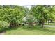 An aerial view of a landscaped red brick home with a well-manicured lawn and mature shade trees at 7629 Candlewood Ln, Indianapolis, IN 46250