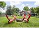 Cozy backyard fire pit area with four red chairs, surrounded by lush greenery and the home's elegant gazebo at 7629 Candlewood Ln, Indianapolis, IN 46250