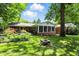 Serene backyard featuring a fire pit, lush greenery, and a charming brick house with a screened porch at 7736 Wawasee Dr, Indianapolis, IN 46250