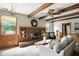 Comfortable living room featuring a brick fireplace, beamed ceilings, and large windows for natural light at 7736 Wawasee Dr, Indianapolis, IN 46250