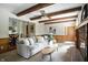 Open-concept living room with beamed ceilings, fireplace, and easy access to the dining area and kitchen at 7736 Wawasee Dr, Indianapolis, IN 46250