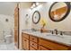 Bathroom with a double sink vanity featuring granite counters, round mirrors, and wood cabinets at 817 Hickory Way, Noblesville, IN 46062
