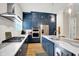 Charming kitchen boasts stainless steel appliances, gas range, quartz countertops, and dark blue cabinets at 906 Berkhamsted Ln, Carmel, IN 46032