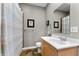 Well-lit bathroom with a modern sink, a large mirror, and a shower featuring neutral colors and decorative artwork at 932 N Broadway St # 4, Indianapolis, IN 46202