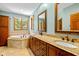 Bathroom featuring double sinks with granite counters, a soaking tub, and tile accents at 10455 Trewithen Ln, Carmel, IN 46032