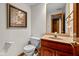 Classic half bathroom with a framed painting, wood vanity, and a large mirror at 10455 Trewithen Ln, Carmel, IN 46032