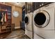 Well-organized laundry room featuring modern washer and dryer, wooden cabinets, and a unique circular window at 1089 Laurelwood, Carmel, IN 46032
