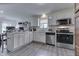 Bright kitchen with ample white cabinetry, stainless appliances, and wood-look flooring at 11117 Waterfield Pl, Indianapolis, IN 46235