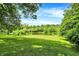 Beautiful, expansive lawn with mature trees leads to a tranquil pond with slide, perfect for outdoor enjoyment at 1155 Cope Rd, Martinsville, IN 46151