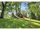 Charming wooden cabin with a slide, nestled amongst mature trees and lush greenery, with an American flag waving proudly at 1155 Cope Rd, Martinsville, IN 46151