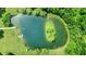 High angle shot of a tranquil pond featuring an island and dock, surrounded by green lawns and trees at 1155 Cope Rd, Martinsville, IN 46151