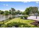 The serene backyard features a lush lawn, landscaping, basketball court, and waterfront views at 12208 Island Dr, Indianapolis, IN 46256