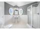 Modern bathroom featuring a frameless glass shower, pedestal sink, tiled floor, and stylish oval windows at 12208 Island Dr, Indianapolis, IN 46256