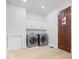 Bright laundry room featuring modern appliances, a wood door, and white cabinets at 12208 Island Dr, Indianapolis, IN 46256