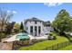 A stunning white home boasts a backyard swimming pool, sport court, lush landscaping and waterfront access at 12208 Island Dr, Indianapolis, IN 46256