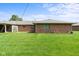 Expansive backyard view with mature green grass and charming brick architecture of this inviting residential property at 1309 Wyoming Way, Anderson, IN 46013