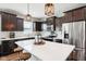 Modern kitchen with dark wood cabinetry, stainless steel appliances, and a white quartz island with seating at 14453 Glapthorn Rd, Fishers, IN 46037