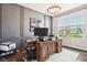 Well-lit office featuring a large desk, window view, and grey accent wall with sports memorabilia at 14453 Glapthorn Rd, Fishers, IN 46037