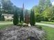Well-maintained front yard featuring mature trees, decorative stones and an American flag at 162 W Robertson Rd, Morgantown, IN 46160