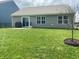 Landscaped backyard with a green lawn, a patio with grill, and sliding glass doors at 213 Drewood Dr, Trafalgar, IN 46181