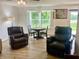 Bright living room boasts wood floors, natural light, and inviting seating area with comfortable armchairs at 213 Drewood Dr, Trafalgar, IN 46181