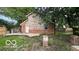 Home's backyard featuring a brick foundation and unfinished patio with mature trees at 252 Ringwood Way, Anderson, IN 46013