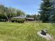 Expansive backyard featuring a fire pit, green lawn, a wooden fence and mature trees at 2937 S Allen Dr, New Palestine, IN 46163