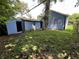 View of home's backyard, showing the house, detached garage, and overgrown grass at 3201 W 22Nd St, Indianapolis, IN 46222