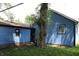 Rear view of the house and detached garage with blue siding, well-maintained lawn and a mature tree at 3201 W 22Nd St, Indianapolis, IN 46222
