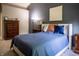 Well-lit bedroom featuring a queen-size bed, two nightstands, neutral colored carpet and dark blue accent wall at 3474 Glen Abbe Ct, Carmel, IN 46032