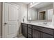 Bathroom featuring double sinks, dark cabinets, and an adjacent room at 3606 Evergreen Way, Zionsville, IN 46077