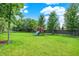 Spacious backyard with lush green grass, mature trees, and a playset for outdoor fun at 3740 Weather Stone Xing, Zionsville, IN 46077
