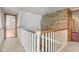 Upstairs hallway with a brick accent wall, wood railing, and neutral carpet at 396 W 500 S, Anderson, IN 46013