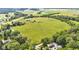 A sprawling green pasture is surrounded by lush trees and neighboring homes in an aerial view at 4535 N Us Hwy 52, Thorntown, IN 46071
