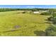Picturesque aerial view of a grassy field with scattered trees, a barn, and clear blue sky at 4535 N Us Hwy 52, Thorntown, IN 46071