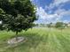 Green backyard with a tree, pond, and other houses in the distance at 4726 Deacon Ln, Indianapolis, IN 46237