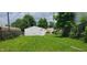 Backyard view of a detached white shed on a grassy lot, bordered by a chain-link fence at 5344 Fletcher Ave, Indianapolis, IN 46219