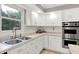 Bright kitchen with white cabinetry, stainless steel appliances, and tile countertops at 58 Penn Pl, Zionsville, IN 46077