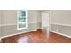 Sunlit living room features hardwood floors, neutral walls with white trim, and a large window with blinds at 58 Penn Pl, Zionsville, IN 46077